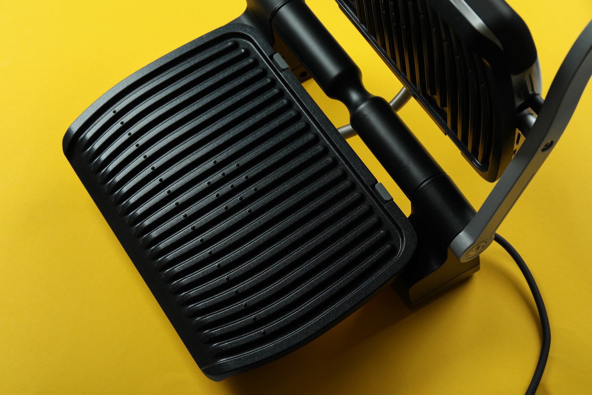 Modern electric grill on yellow background, close up